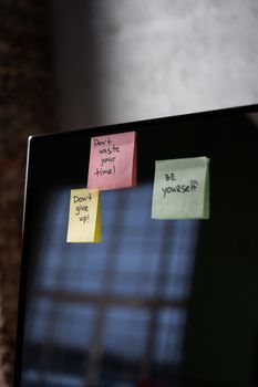 Close-up of sticky notes on a computer screen with motivational messages.