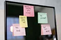 Colorful sticky notes with motivational messages on a mirror reflecting positivity.