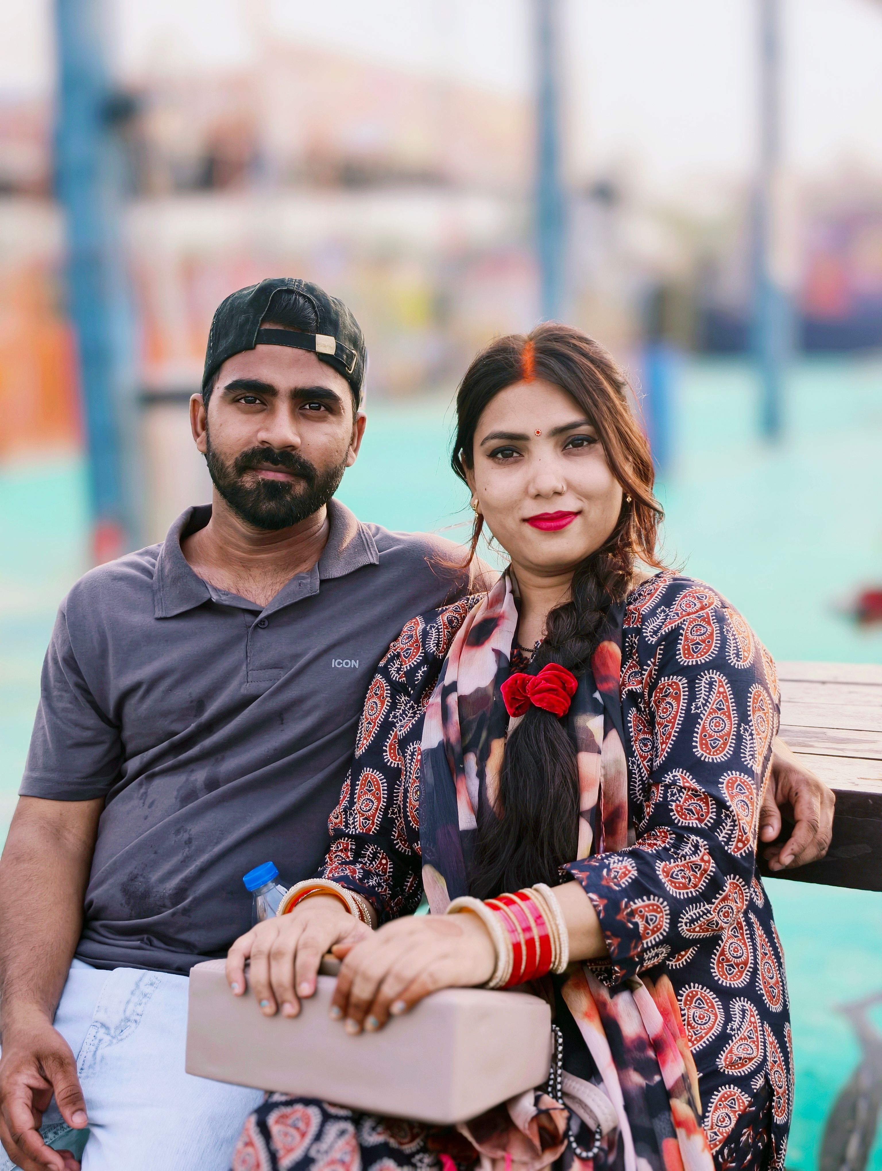 A couple seated peacefully outdoors, showcasing cultural attire and enjoying a relaxing time together.
