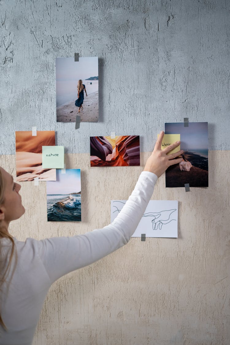 A Woman Sticking Photos And Notes On A Wall