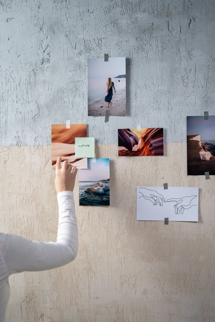 A Person Sticking Photos On A Wall