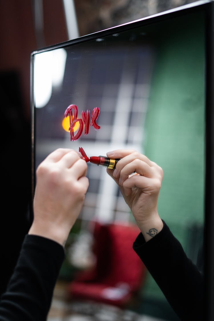 Person Writing On A Mirror Using A Red Lipstick