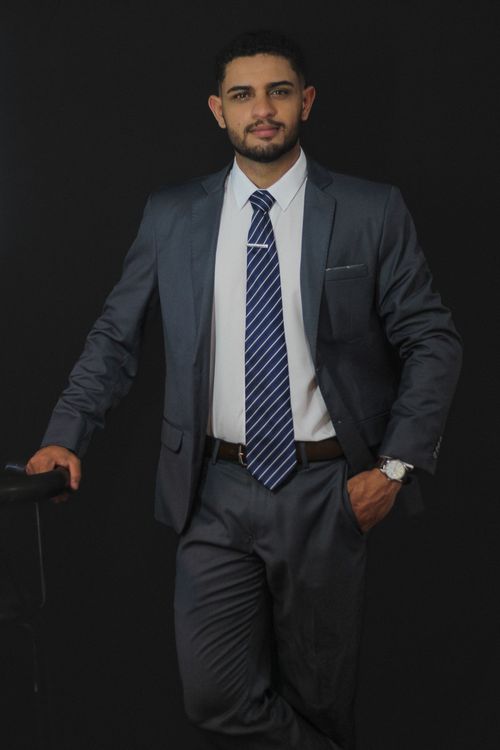 Free Portrait of a confident businessman in a suit and tie against a black backdrop. Stock Photo