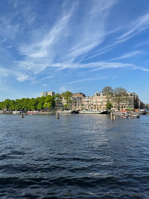 Free Explore the serene canals and iconic architecture of Amsterdam under a clear blue sky. Stock Photo