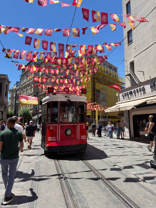 Free İstanbul's iconic red tram navigating İstiklal Avenue amidst vivid street decorations. Stock Photo