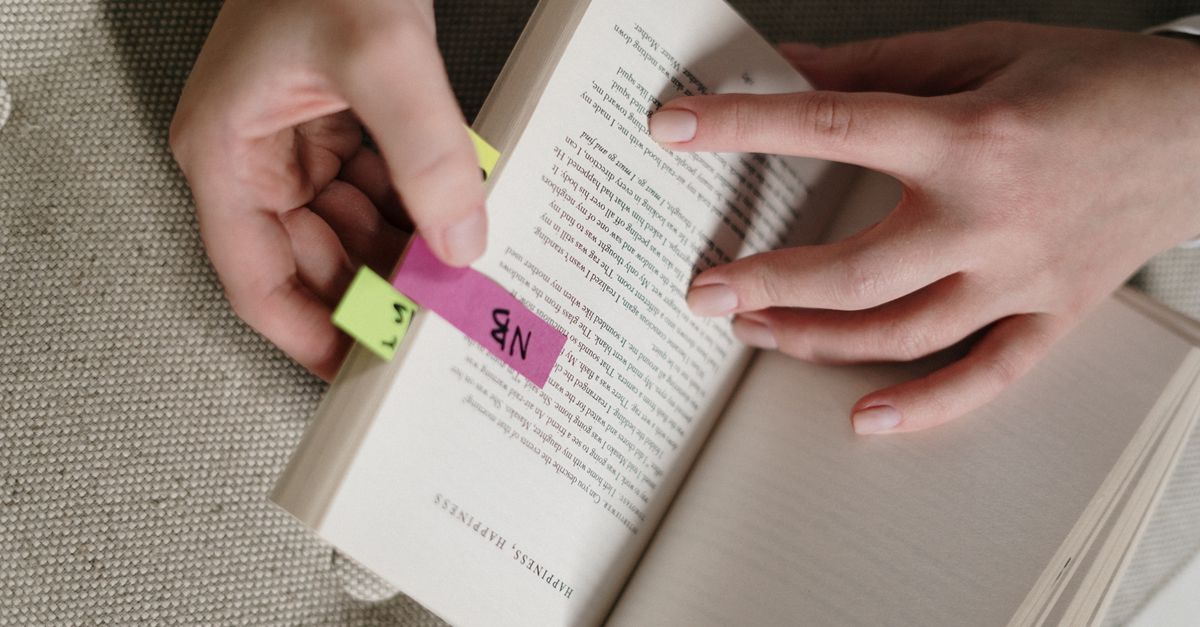 person reading a medical textbook with sticky notes, looking curious