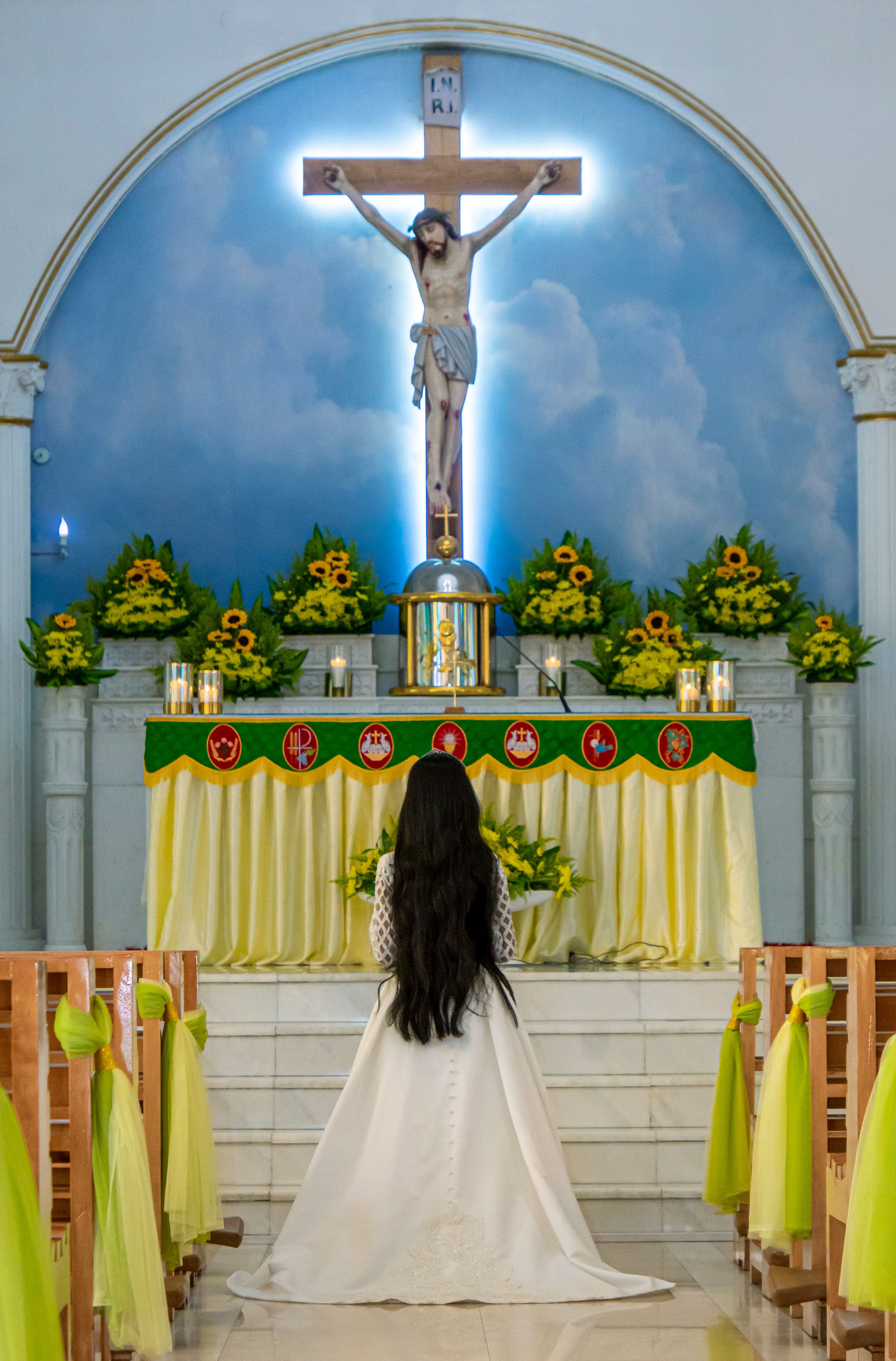 Woman in white kneeling at church altar with crucifix