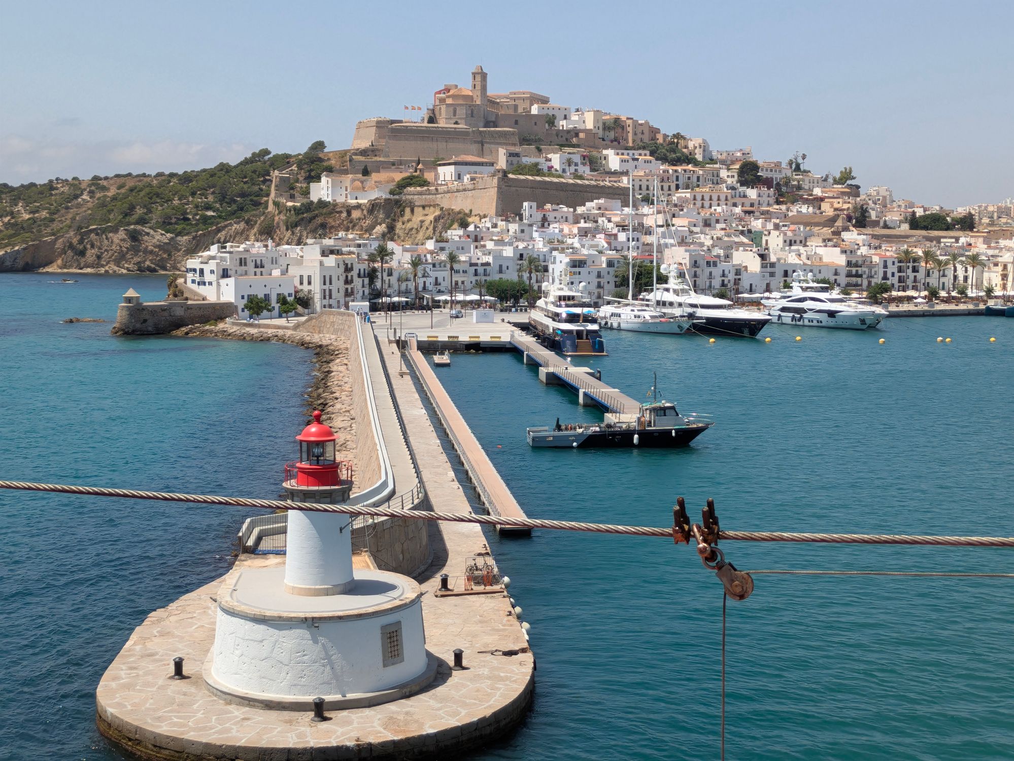 Stunning view of Ibiza harbor featuring a lighthouse with the historic old town in the background.