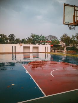 Empty basketball court with wet surface after rain, showing vibrant colors and reflective water.