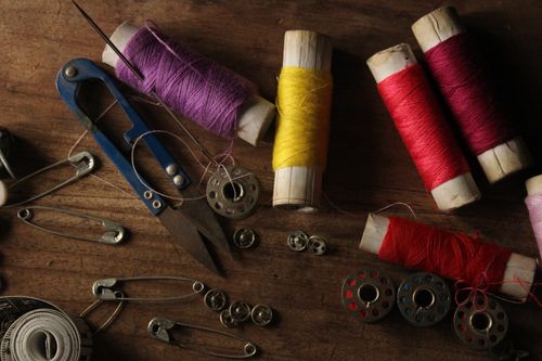 Free Vivid spools of thread and sewing accessories artistically arranged on wood. Stock Photo