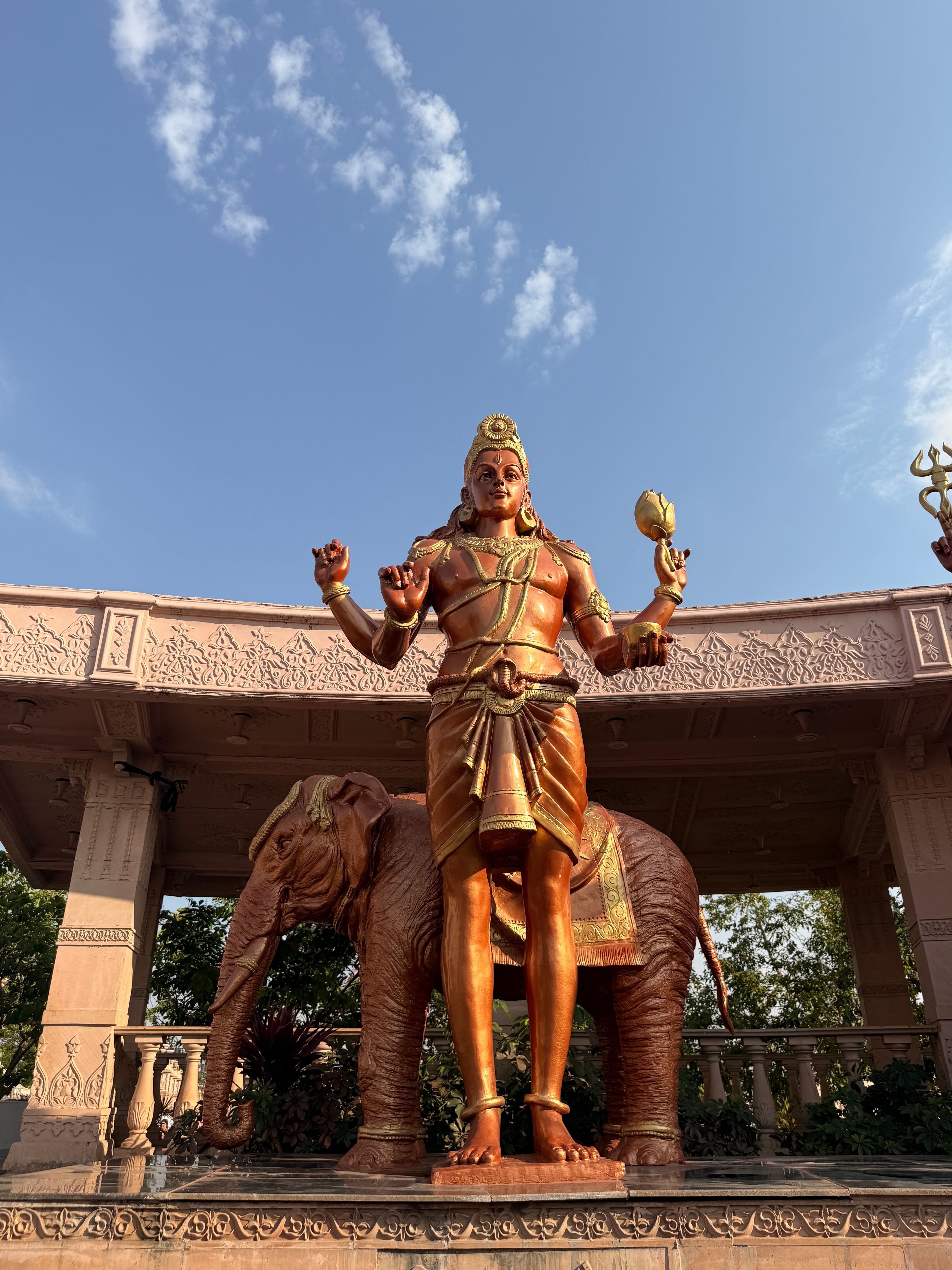 Vibrant golden statue of Lord Hanuman with elephant in Ujjain, India temple setting.
