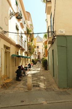Sunny alleyway with quaint cafes and architecture in a Mediterranean city.