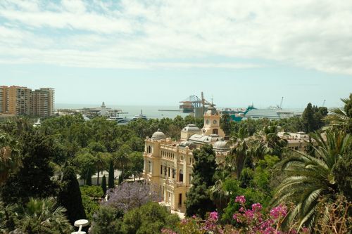 Free Explore Málaga's vibrant port and historic architecture from a lush, elevated vantage point. Stock Photo