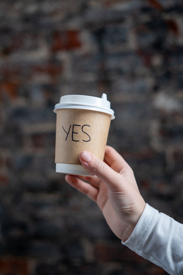 A Person Holding A Paper Cup With The Word Yes