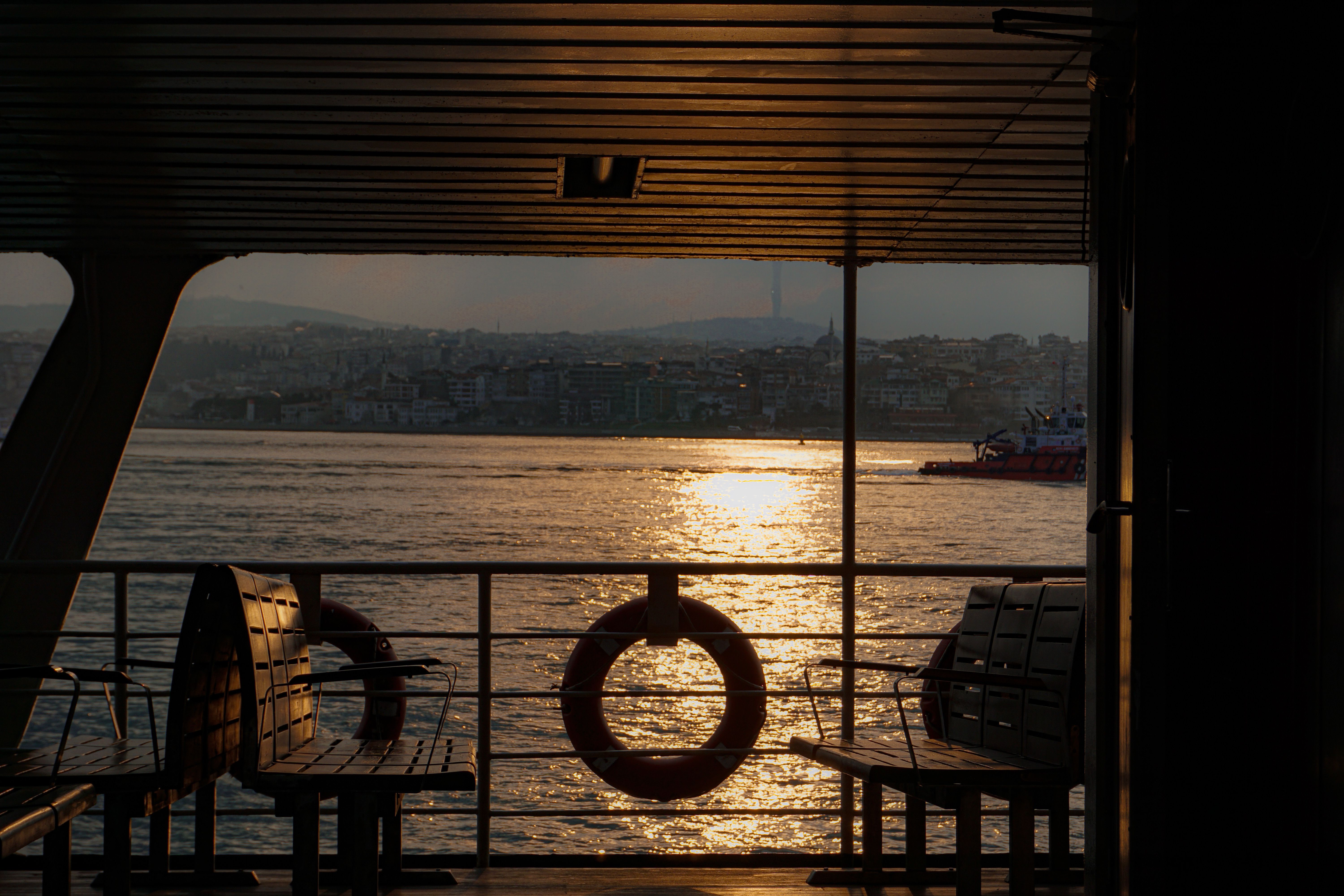 Serene view from ferry during sunset on Istanbul's Bosphorus, capturing cityscape and shimmering water.