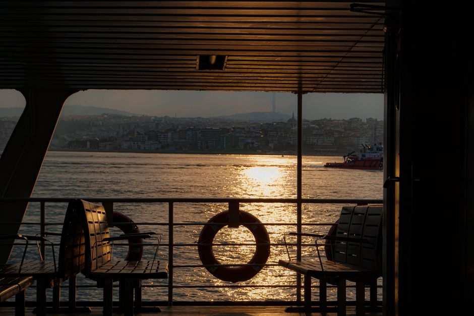 Serene view from ferry during sunset on Istanbul's Bosphorus, capturing cityscape and shimmering water.