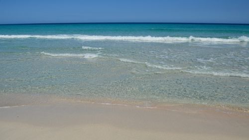 Free Tranquil beach scene in Corsica, with clear waters and white sand under a bright blue sky. Stock Photo