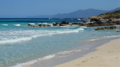 Free Discover the tranquil beauty of a wild Corsican beach with clear waters and rocky shores. Stock Photo