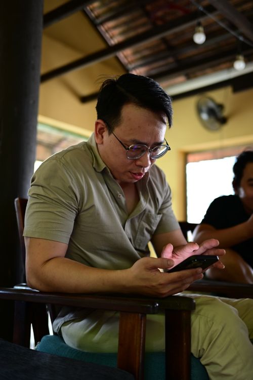 Free Man focused on smartphone while sitting indoors, conveying technology engagement. Stock Photo