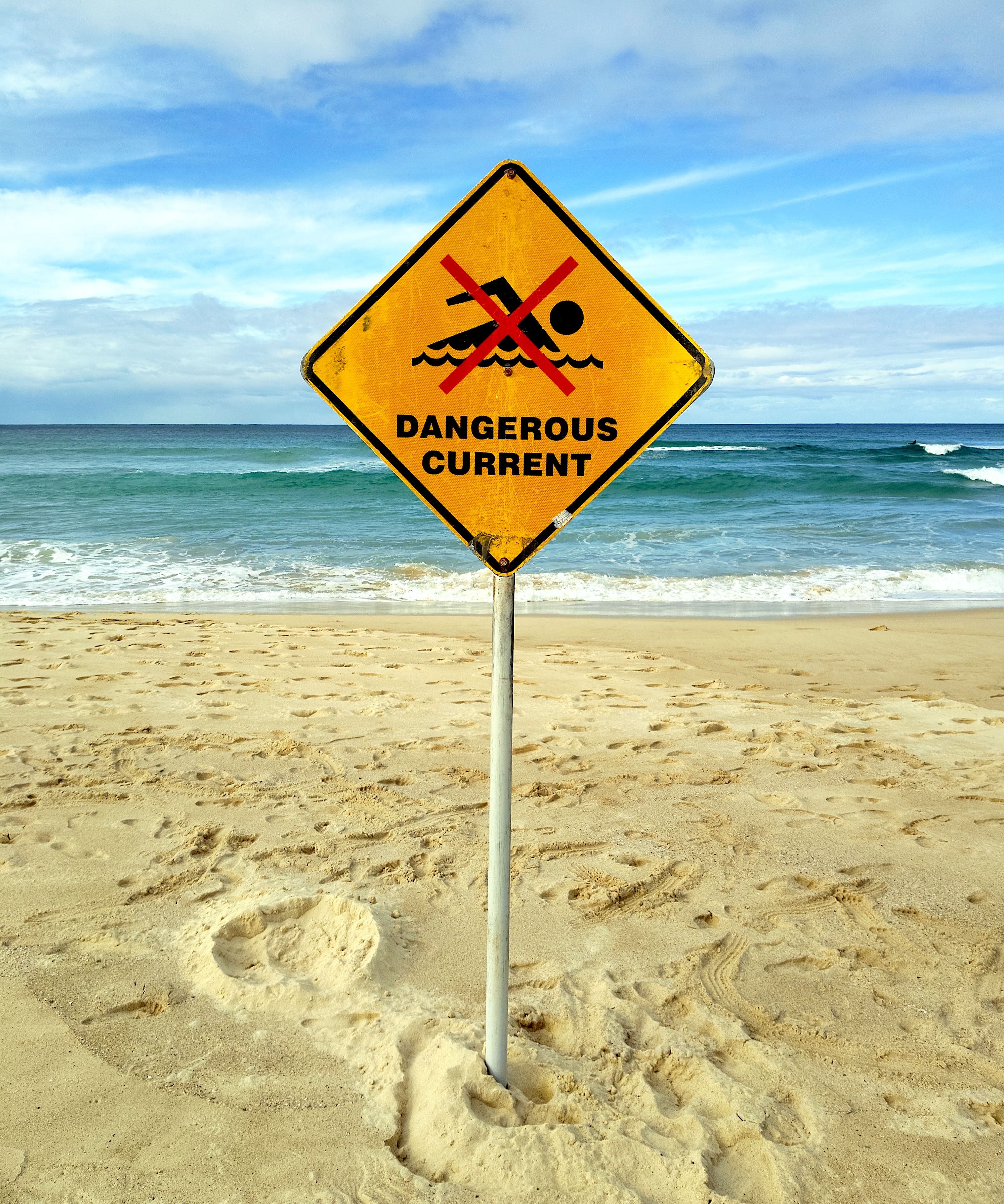 A warning sign at Bondi Beach cautioning about dangerous currents. Perfect for safety and travel themes.