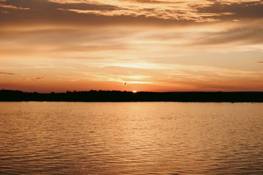 A tranquil sunset over a calm body of water with a warm, golden sky.