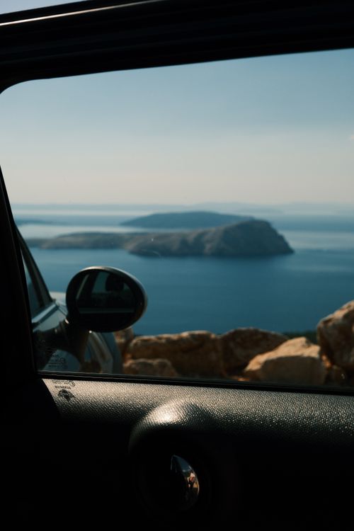Free Tranquil ocean view framed by a car window, highlighting a serene island landscape. Stock Photo