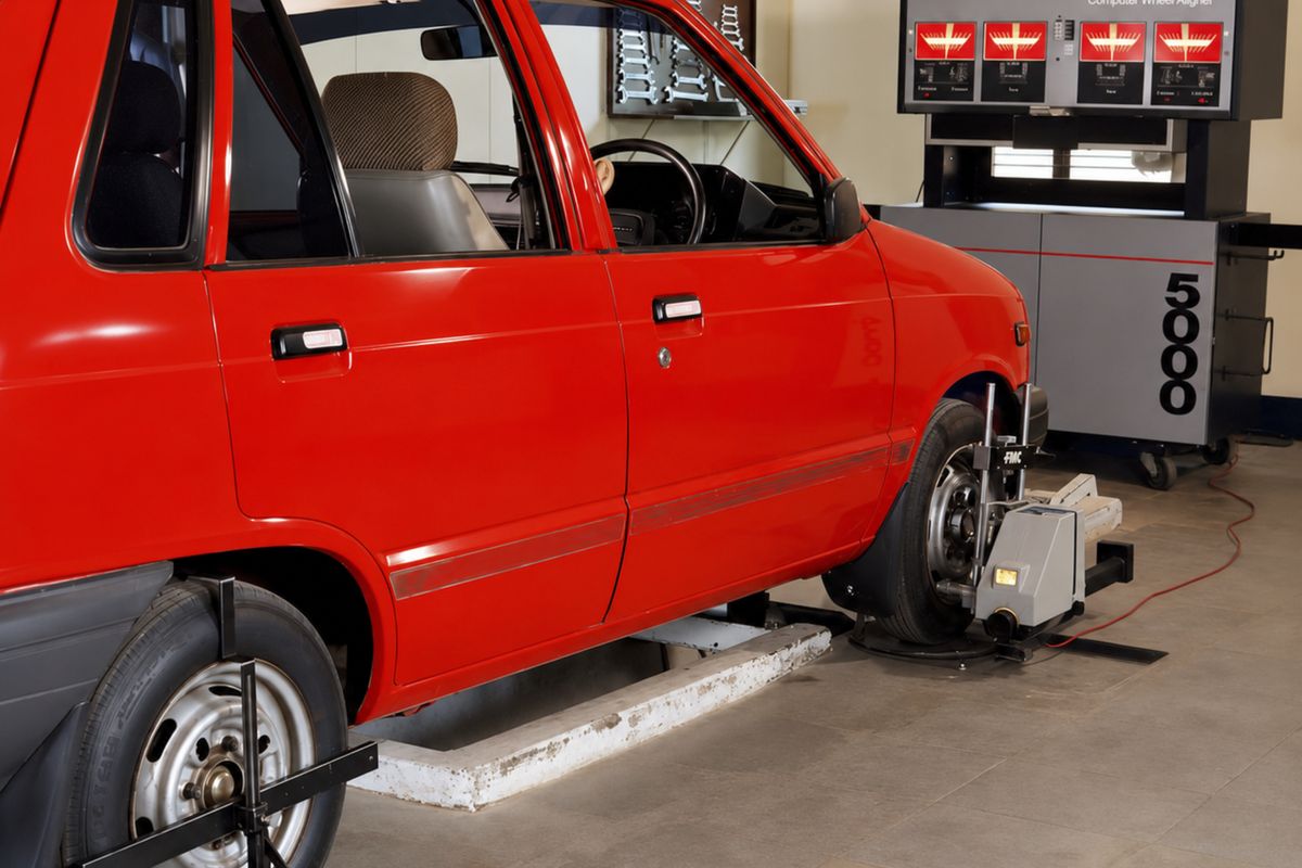 Red compact car on a computerized wheel alignment rack with sensors mounted on the wheels