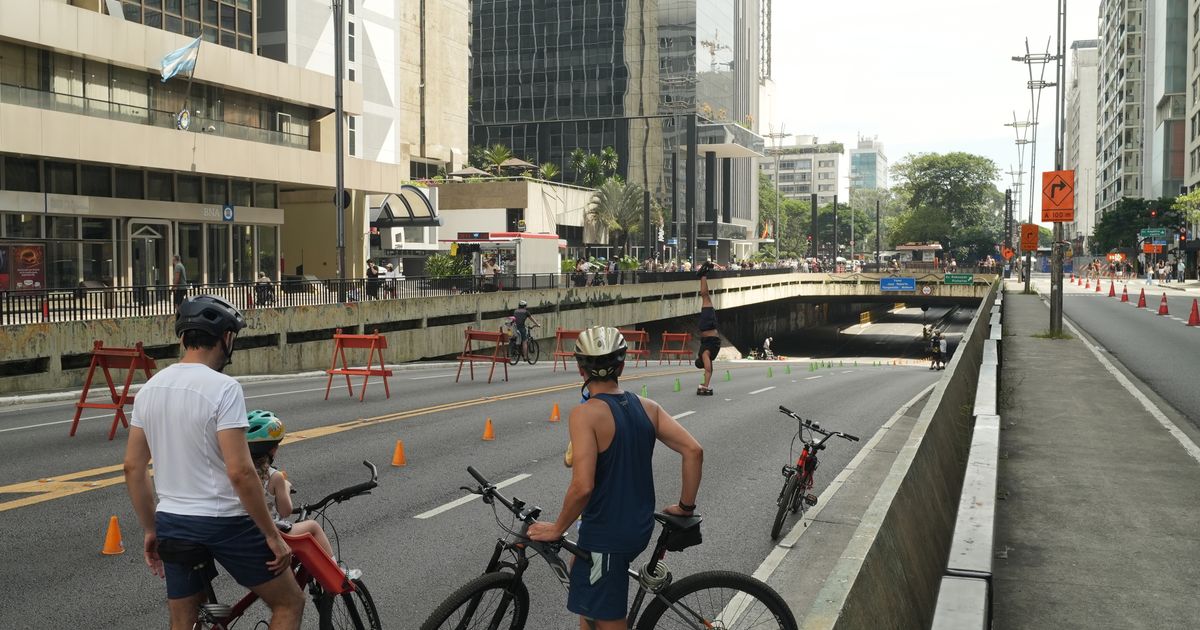 Pessoas pedalando na Avenida Paulista em São Paulo durante um evento sem carros, mostrando a vida urbana.