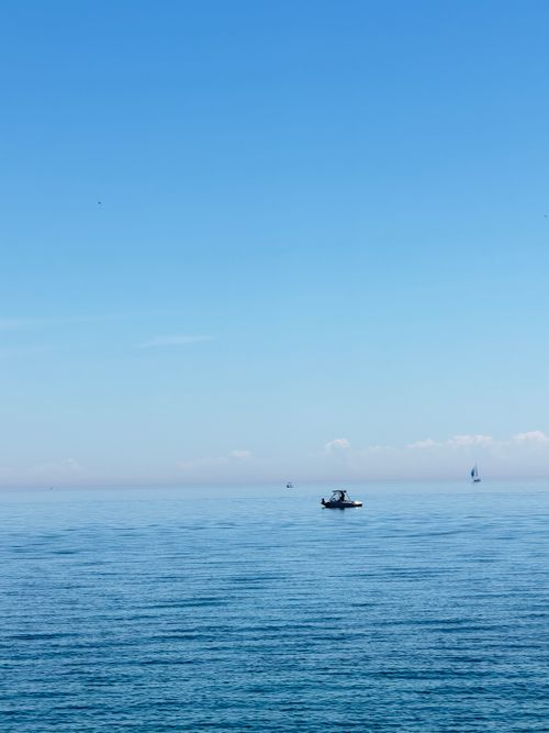 Free Serene view of boats floating on calm sea under a clear blue sky, offering a peaceful and relaxing scenery. Stock Photo