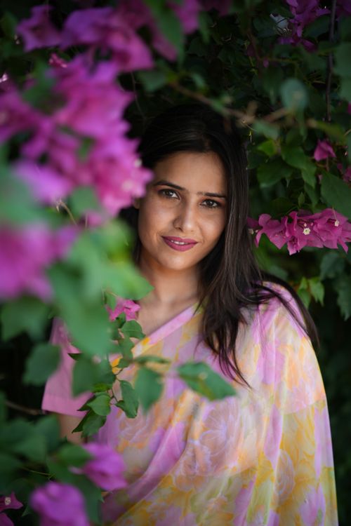 Free Elegant portrait of a woman in a saree surrounded by vibrant bougainvillea blooms. Stock Photo