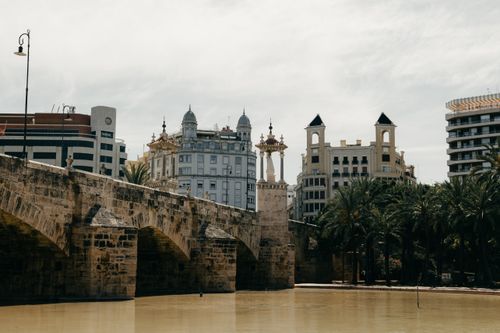 Free Scenic view of a historic stone bridge with modern buildings in Valencia, Spain. Stock Photo