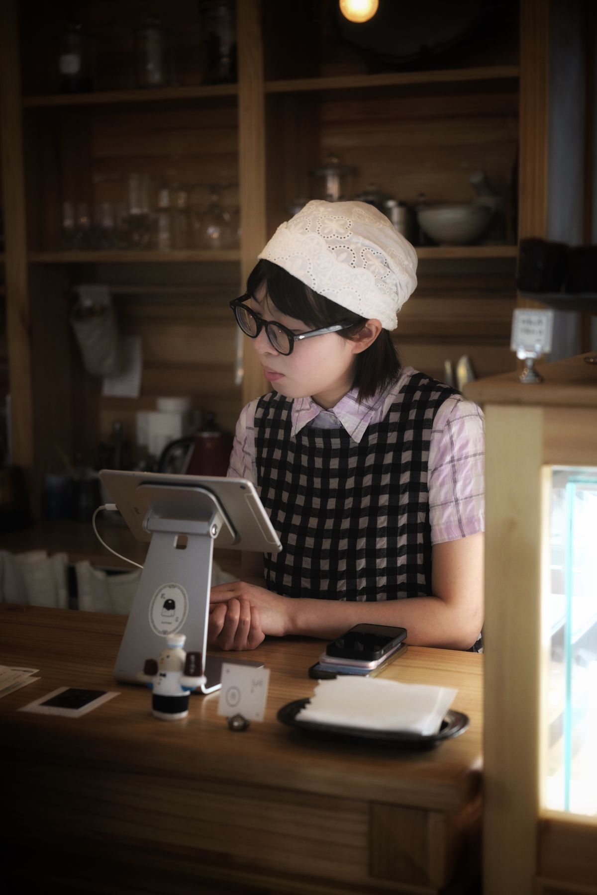 A barista using a tablet till at a coffee shop counter