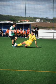 Two young athletes in action during a youth soccer match on a sunny day.