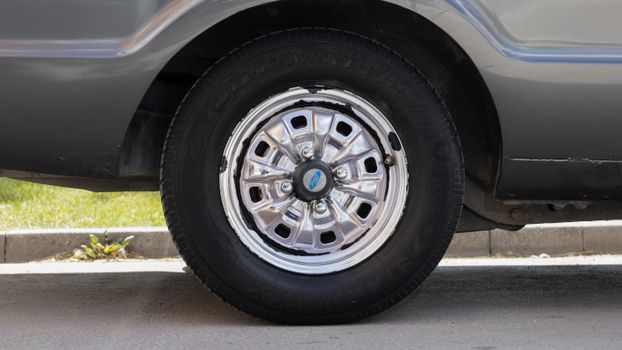 Detailed view of a car tire with a shiny chrome hubcap, captured outdoors in Konya, Türkiye.