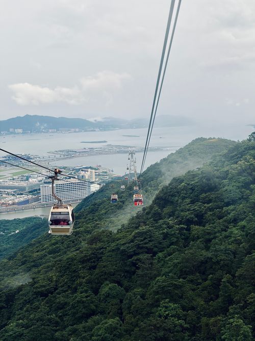 Free A beautiful scenic cable car ride over lush mountains with a view of the ocean and distant cityscape. Stock Photo