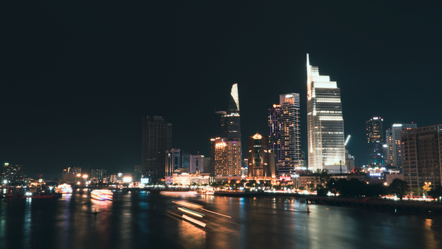 Night view of dynamic city skyline reflecting on river waters.