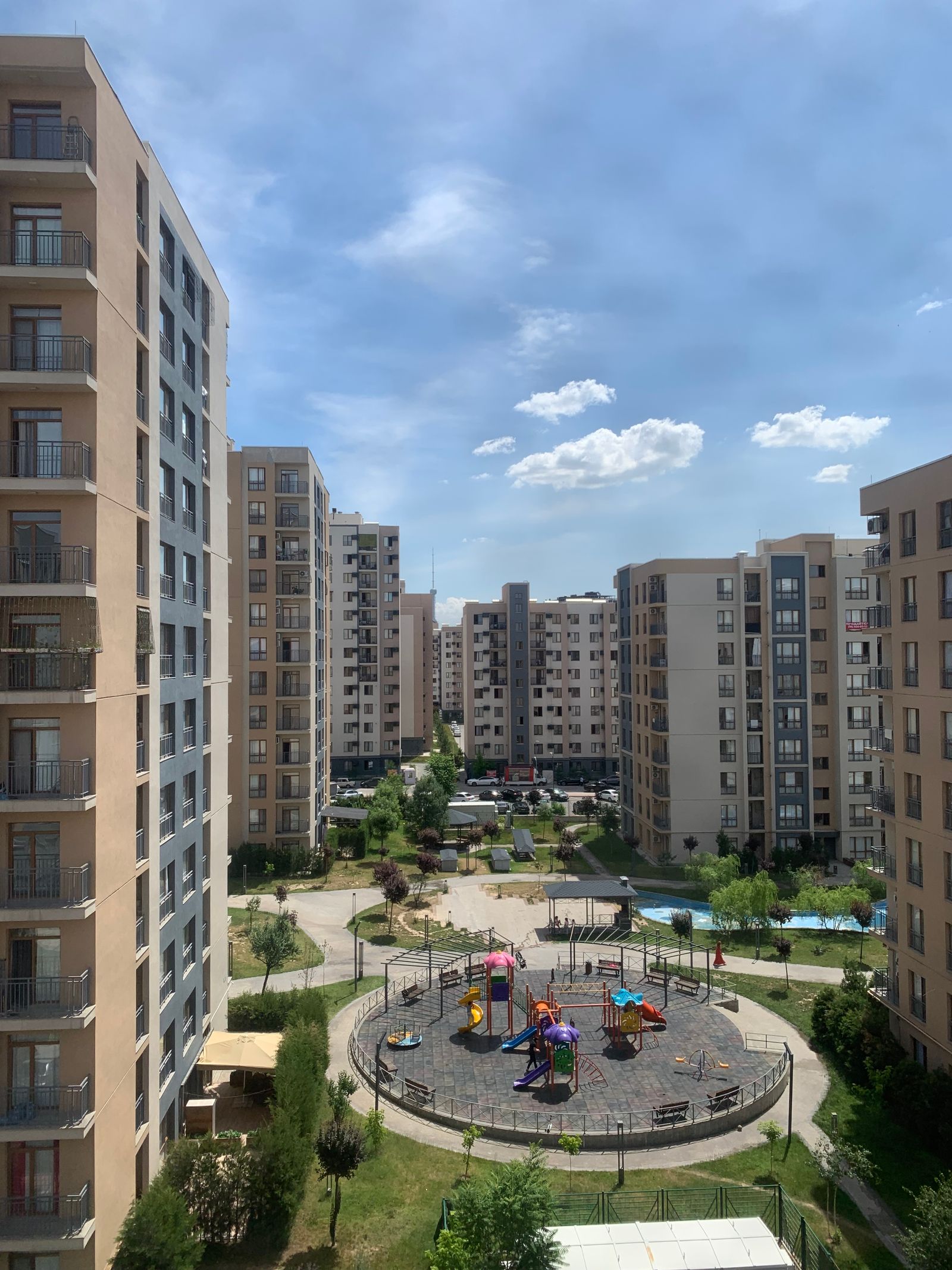 Mid-rise apartment buildings arranged around a central playground and lawn