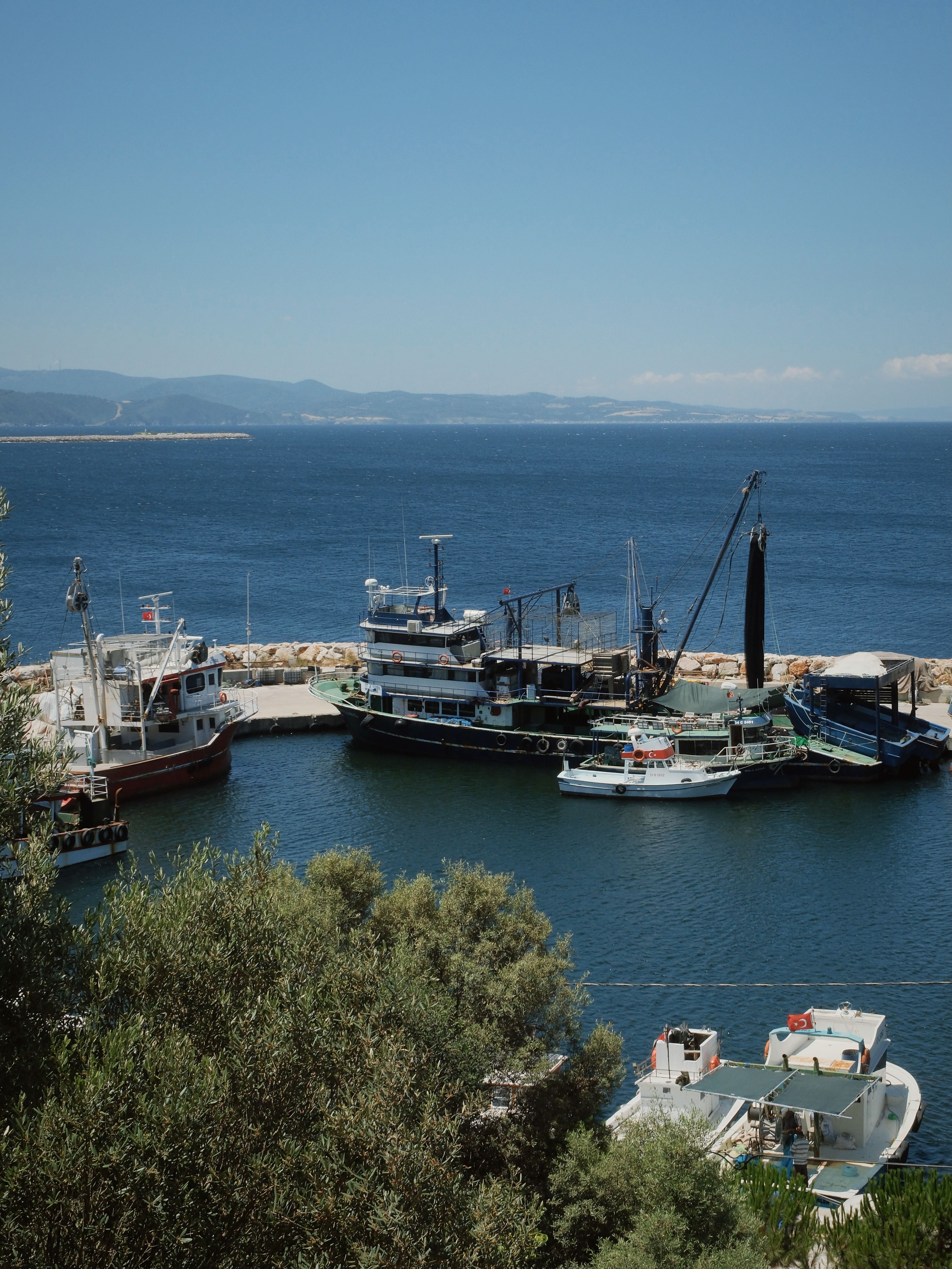 Explore a picturesque harbor scene with boats and blue waters in Çanakkale, Türkiye.