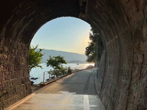 Free Discover the serene beauty of Herceg Novi's seaside path at sunset, viewed through a rustic tunnel. Stock Photo