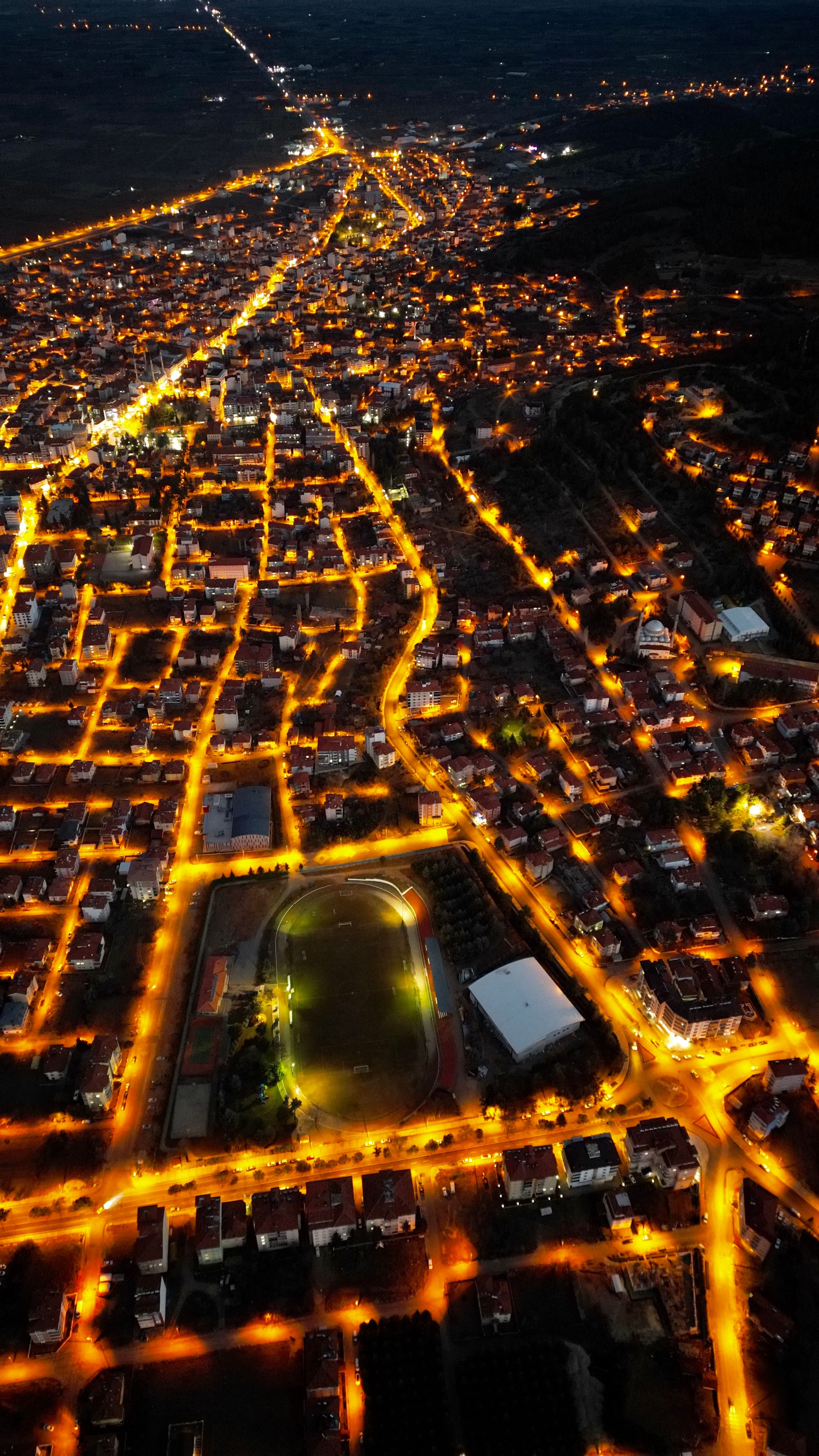 Stunning aerial view of a city at night with golden-lit streets, showcasing urban design and nightlife.