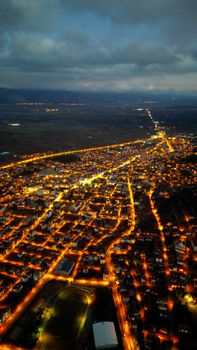 Stunning aerial night view of a city landscape with vibrant street lights and distant mountains.