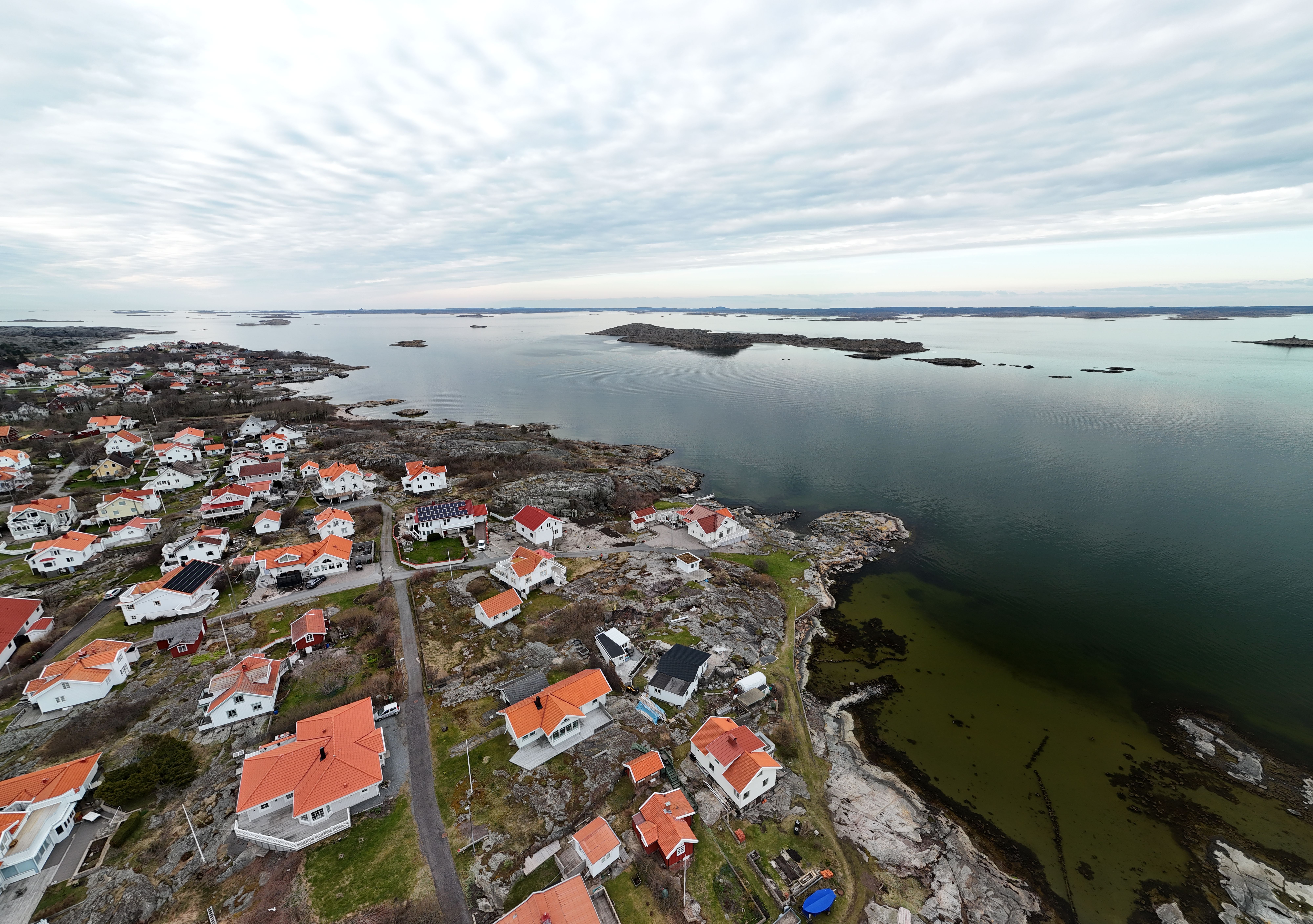 Explore the stunning aerial view of a picturesque Swedish coastal village with red-roofed houses and serene waters.