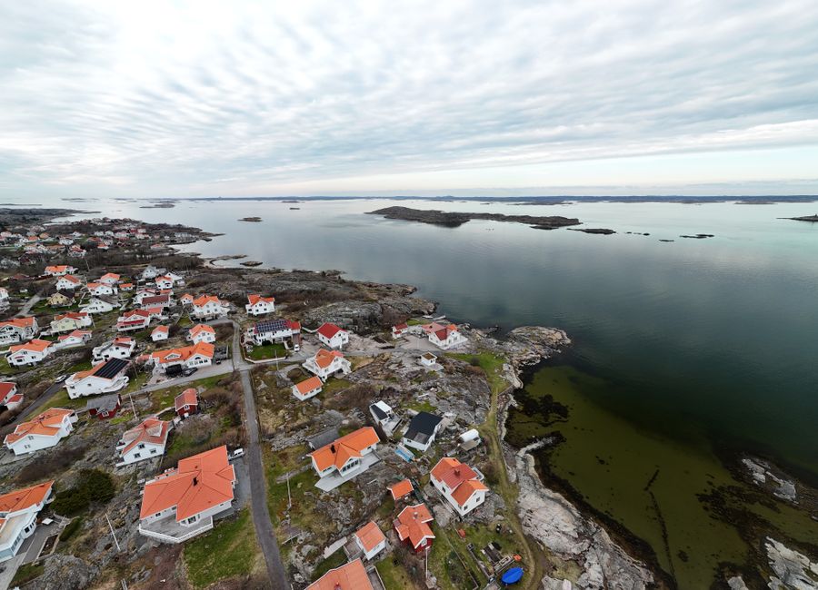 Explore the stunning aerial view of a picturesque Swedish coastal village with red-roofed houses and serene waters.