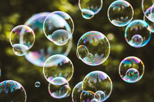 Free Vibrant soap bubbles floating in the air against a green park backdrop, capturing a sense of joy and freedom. Stock Photo