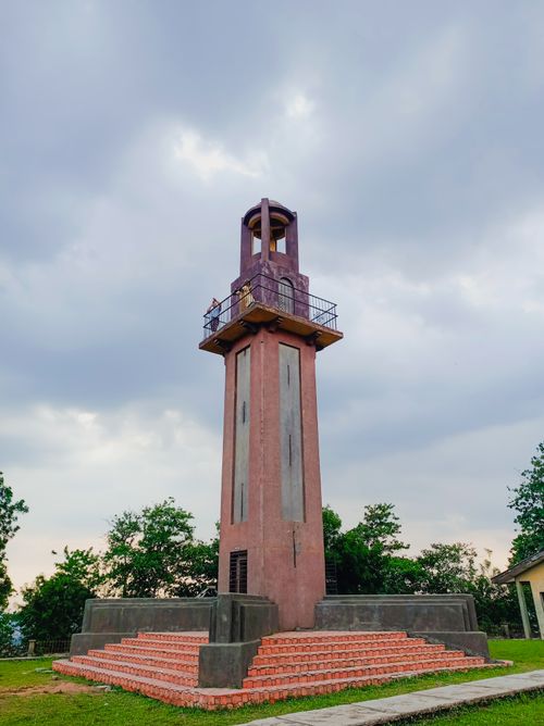 Free An imposing observation tower stands under a dramatic cloudy sky, surrounded by greenery. Stock Photo