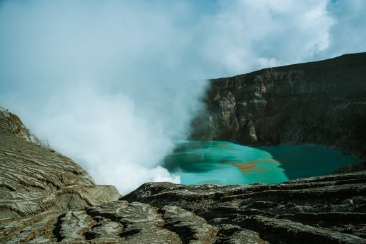 Stunning view of Ijen Crater’s turquoise lake with steaming sulfur gases in East Java, Indonesia.