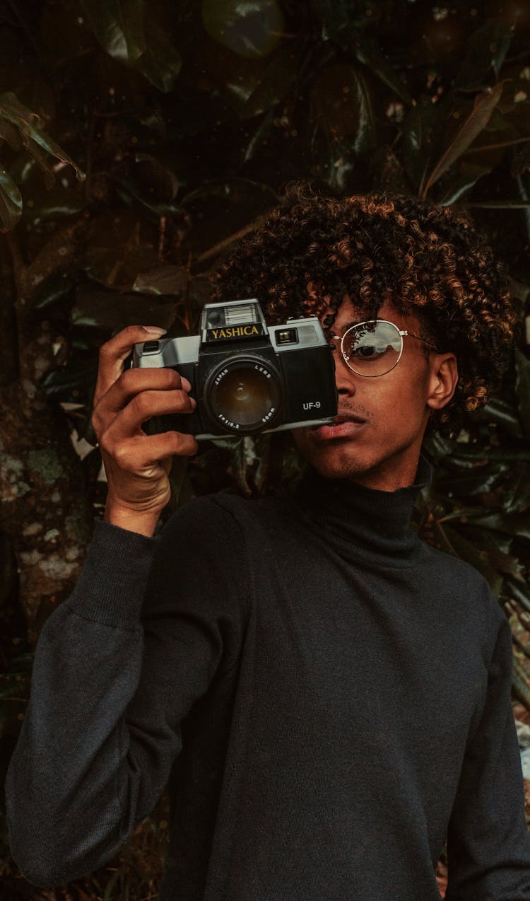 Focused Black Teenager Using Vintage Photo Camera In Garden