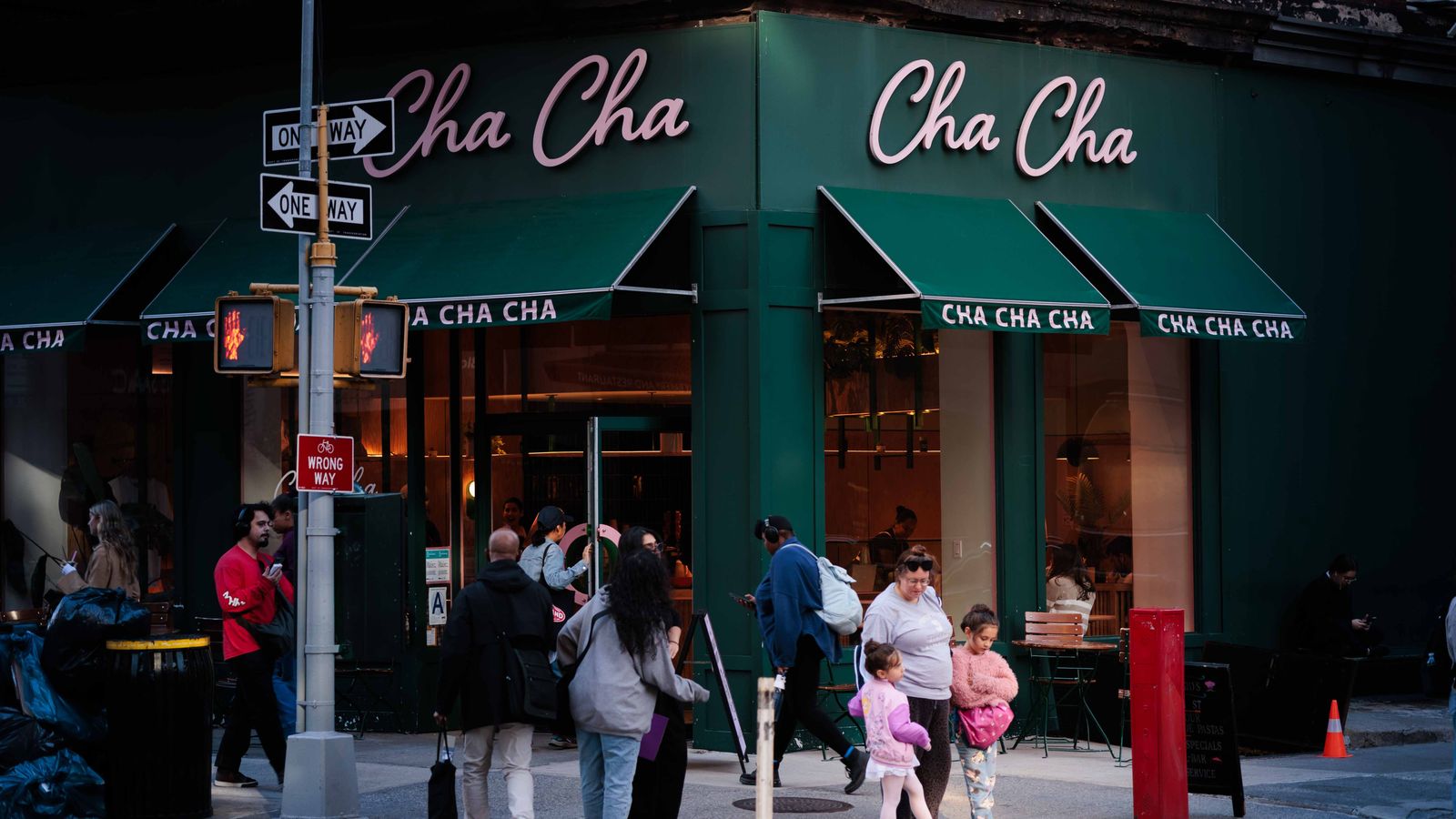 People walking by the Cha Cha Café in New York City, showcasing vibrant urban life.