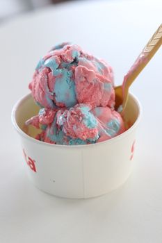 Colorful pink and blue ice cream in a cup with a spoon, perfect for summer.