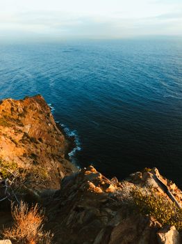 Captivating rocky cliffs overlooking the ocean at golden hour, perfect for nature lovers.